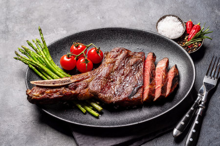 Medium rare grilled Tomahawk beef steak with asparagus on plateの写真素材