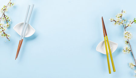 Table adorned with cherry blossom branch and chopsticks, epitomizing Japanese food culture, providing ample copy spaceの写真素材