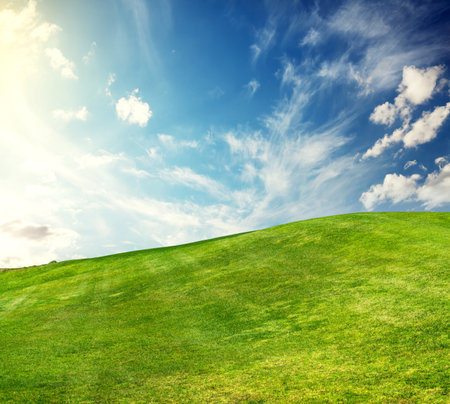 A sunny landscape unfolds, featuring meticulously trimmed green grass under a majestic sky, evoking a sense of tranquility and natural beautyの写真素材