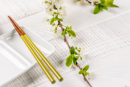 Empty plate on table adorned with cherry blossom branch and chopsticks, epitomizing Japanese food culture, providing ample copy spaceの写真素材