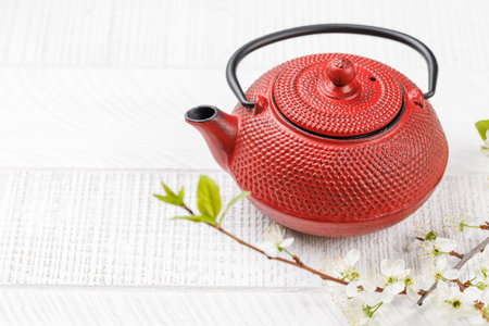 Table with teapot adorned with cherry blossom branch, epitomizing Japanese food cultureの写真素材