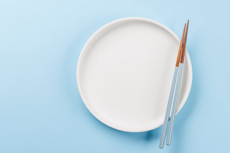 Table with empty plate and chopsticks, epitomizing Japanese food culture, providing ample copy spaceの写真素材