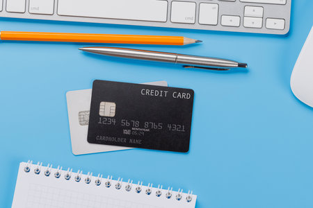 Black credit card on office table with laptop and supplies. Flat lay. Premium banking conceptの写真素材
