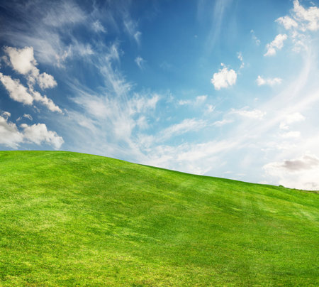 A sunny landscape unfolds, featuring meticulously trimmed green grass under a majestic sky, evoking a sense of tranquility and natural beautyの写真素材