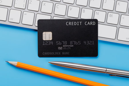 Black credit card on office table with laptop and supplies. Flat lay. Premium banking conceptの写真素材