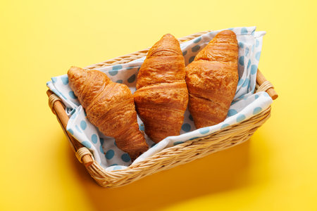 Fresh croissants in basket on yellowの写真素材
