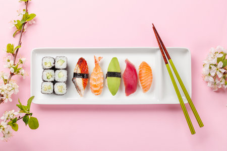 Sushi plate on table adorned with cherry blossom branch and chopsticks, epitomizing Japanese food cultureの写真素材