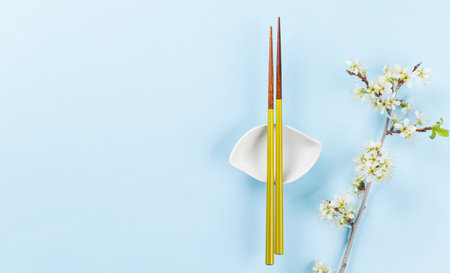 Table adorned with cherry blossom branch and chopsticks, epitomizing Japanese food culture, providing ample copy spaceの写真素材