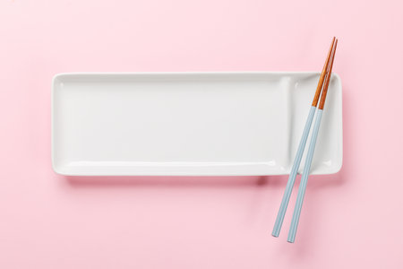 Empty plate on table adorned with cherry blossom branch and chopsticks, epitomizing Japanese food culture, providing ample copy spaceの写真素材