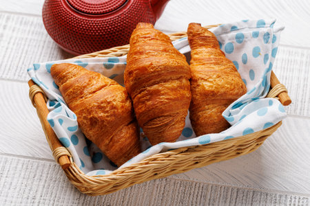 Fresh croissants in basket on wooden boardの写真素材