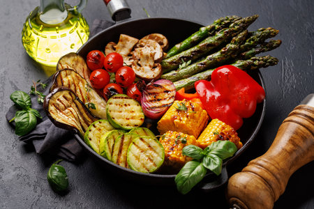 Assorted grilled vegetables on a frying pan, showcasing a colorful and healthy mealの写真素材