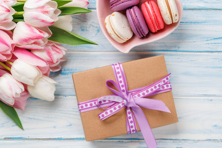 Pastel colorful tulips and vibrant macaroons fill a heart-shaped bowl, offering a delightful and charming scene perfect for celebrations or joyful momentsの写真素材