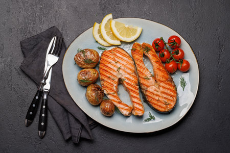 Grilled salmon steaks and potatoes on a plate, a mouthwatering delightの写真素材