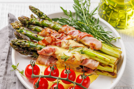 Grilled asparagus with bacon and egg sauce on a plateの写真素材