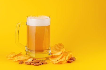Beer and potato chips. Over yellow background with copy spaceの写真素材