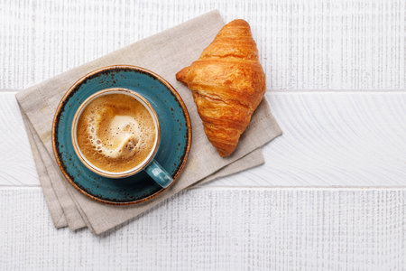 Cappuccino coffee and fresh croissant on wooden table. Flat lay with copy spaceの写真素材
