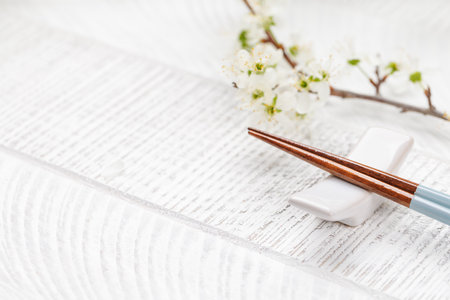 Table adorned with cherry blossom branch and chopsticks, epitomizing Japanese food culture,...