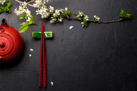Table adorned with cherry blossom branch and chopsticks, epitomizing Japanese food culture, providing ample copy spaceの写真素材