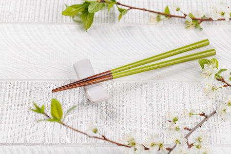 Table adorned with cherry blossom branch and chopsticks, epitomizing Japanese food culture, providing ample copy spaceの写真素材