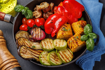 Assorted grilled vegetables on a frying pan, showcasing a colorful and healthy mealの写真素材