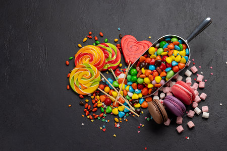 Various colorful candies, lollipops, and macaroons. Flat lay over stone background with copy spaceの写真素材
