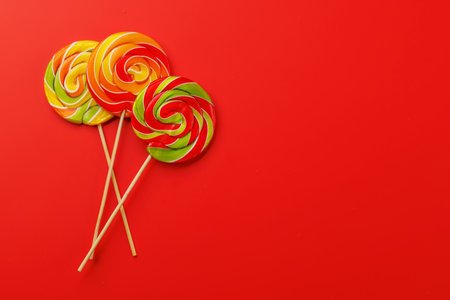 Various colorful candies, lollipops. Flat lay over red background with copy spaceの写真素材