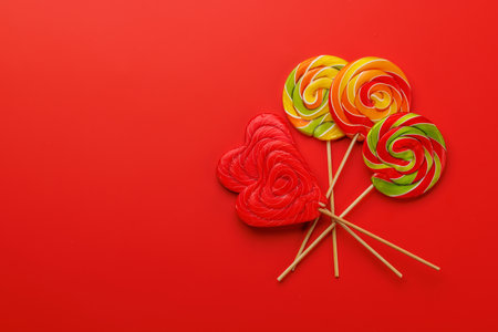 Various colorful candies, lollipops. Flat lay over red background with copy spaceの写真素材