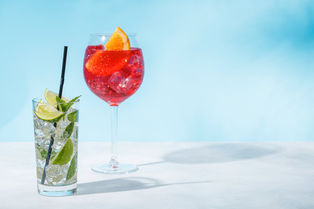 A variety of cocktails arranged on a table against a light blue background, enhanced by sunny glares and playful shadowsの写真素材