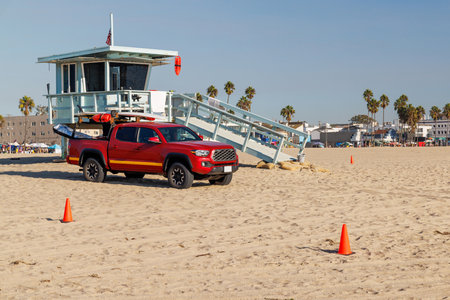 Classic lifeguard tower paired with a rescue vehicle parked nearby on a sandy beach under a clear...