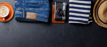 A travel items and clothes arranged on a dark background, flat lay style, with copy space for your...