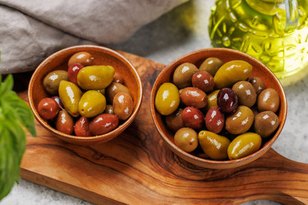 An assortment of various olives presented in a bowl, showing different colors, textures, and flavorsの写真素材