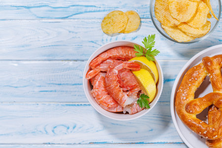 A vibrant photo showing various beer snacks and fast food items, including crispy potato chips, and salty pretzels, fresh shrimps. With copy spaceの写真素材