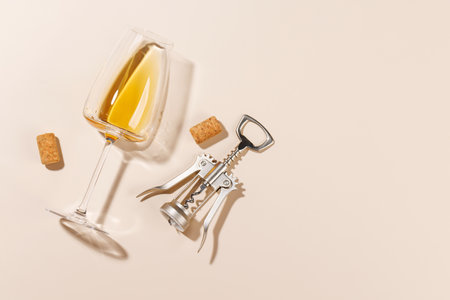 Wine glass alongside a corkscrew and several corks, all arranged on a bright background. The hard...
