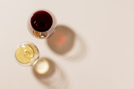 Two wine glasses arranged on a bright background. The hard light creates sharp shadows, adding a dramatic effect to the scene, emphasizing the shapesの写真素材