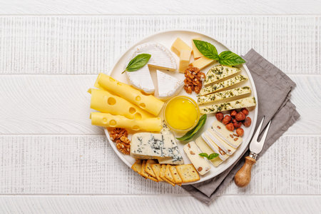 An assortment of various cheeses arranged on a plate, highlighting different textures, colours, and types, perfect for a tasting or appetizerの写真素材