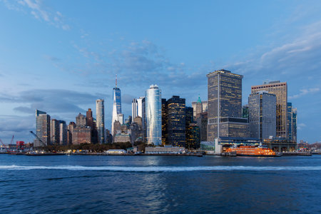 A vibrant sunset panorama of Manhattan downtown skyline, viewed from the river, with skyscrapers illuminated by warm, golden huesの写真素材