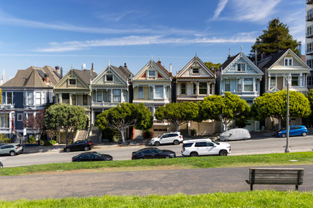 The Painted Ladies, a row of iconic Victorian houses in San Francisco, set against a backdrop of the city skyline. A quintessential view blending historic architecture with modern urban lifeの写真素材