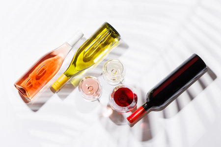Three wine glasses filled with red, white, and rose wine, standing gracefully on a bright, minimalist background. A vibrant display of wine's variety and eleganceの写真素材