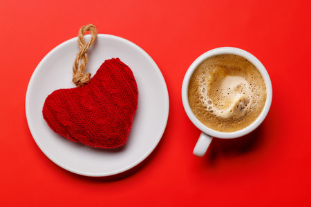 A delightful combination of a steaming coffee cup and a heart-shaped gift, ideal for Valentine's Day moments or romantic gesturesの写真素材