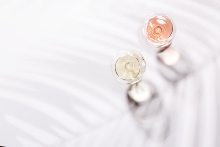 Two wine glasses filled with rose and white wine, standing gracefully on a bright, minimalist background. A vibrant display of wine's variety and eleganceの写真素材