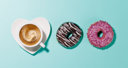 An assortment of vibrant donuts with colorful toppings and a coffee cup on a heart-shaped saucer, arranged on a blue background in a flat lay style, perfect for a Valentines Day cardの写真素材