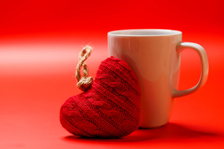 A delightful combination of a steaming coffee cup and a heart-shaped gift, ideal for Valentine's Day moments or romantic gesturesの写真素材