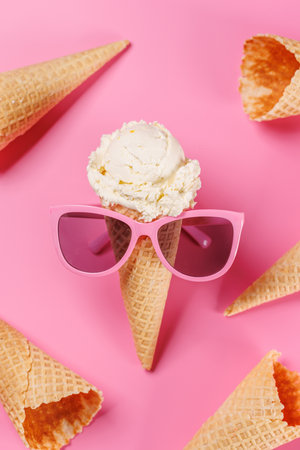 A playful ice cream cone wearing stylish sunglasses, set against a vibrant pink background, radiating summer vibes and funの写真素材
