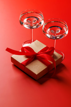 A glasses of champagne elegantly paired with a gift box, set against a romantic backdrop, creating the perfect Valentine's Day mood for celebration and loveの写真素材