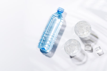 Crystal-clear glasses filled with chilled water and ice cubes, elegantly displayed against a bright white background, exuding freshness and simplicityの写真素材