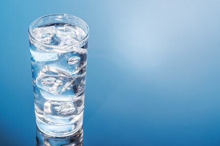 A clear glass filled with chilled water and ice cubes, creating a refreshing and cool drink. The perfect symbol of hydration and freshnessの写真素材