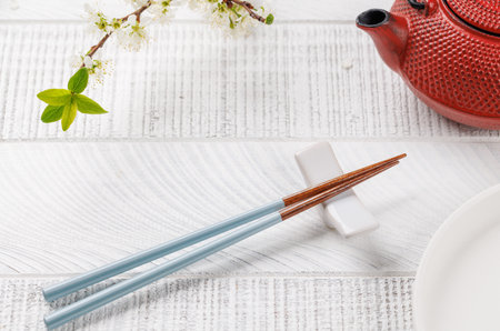 Table adorned with cherry blossom branch and chopsticks, epitomizing Japanese food culture, providing ample copy spaceの写真素材