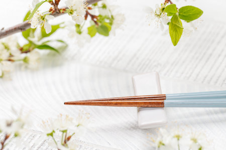 Table adorned with cherry blossom branch and chopsticks, epitomizing Japanese food culture, providing ample copy spaceの写真素材