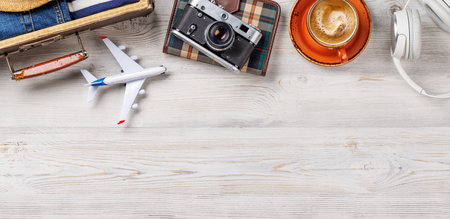A travel bag with clothes, sun hat, flip flops, and a camera arranged on a wooden background, flat lay style, with copy space for your productの写真素材