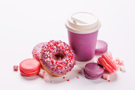 A cheerful display of colorful macarons, donuts, and a paper coffee cup on a white background. A sweet and vibrant setup for dessert or coffee themesの写真素材